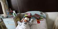 O menino, que ficou cego, em sua cama no hospital, com a região dos olhos cobertas por uma faixa  Foto: AFP