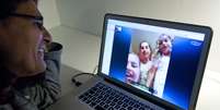 Mulher usa o Skype para se comunicar com a família em Estocolmo, na Suíça  Foto: AFP