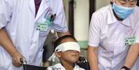 Médico e enfermeira empurram Cadeira de rodas de Guo Bin, 6 anos, em hospital de Taiyuan. O menino, que teve os olhos arrancados após ser drogado por uma mulher não identificada, está em recuperação no hospital. A suspeita ainda é procurada pelas autoridades  Foto: AP