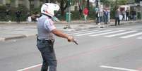 Policial atira para o chão após ser cercado por grupo de manifestantes, em São Paulo  Foto: Rocha Lobo / Futura Press