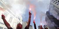 Manifestantes seguram sinalizadores durante protesto  Foto: Reuters