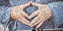 Painel gigante da campanha de Merkel destaca o já tradicional gesto que Merkel faz com as mãos em formato de diamante  Foto: AFP