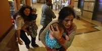 <p>Mulheres carregando crianças são retiradas de shopping center em Nairóbi</p>  Foto: Goran Tomasevi / Reuters