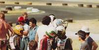 <p>Terry Fullerton (macacão vermelho) conversa com Ayrton Senna (macacão preto) no Circuito de Jesolo, Itália, em 1979; Senna ainda corria com o capacete antigo, cinza com detalhes em verde e amarelo</p>  Foto: Divulgação