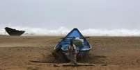 Pescadores amarram seu barco na costa antes de ir para um local mais segura, pr&oacute;ximo &agrave; vila de Donkuru, no Estado de Andhra Pradesh, sul da &Iacute;ndia. Um forte ciclone avan&ccedil;ou sobre a costa leste da &Iacute;ndia neste s&aacute;bado, matando pelo menos cinco pessoas e for&ccedil;ando cerca de meio milh&atilde;o a irem para abrigos lotados enquanto a tempestade amea&ccedil;a deixar uma trilha de devasta&ccedil;&atilde;o em &aacute;reas rurais e vilas de pescadores. 12/10/2013.  Foto: Adnan Abidi / Reuters