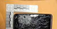 <p>Imagem divulgada pela polícia mostra o telefone destruído pelo tiro</p>  Foto: AP