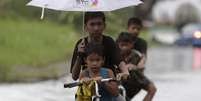 Crianças circulam pelas ruas inundadas de Taguig   Foto: EFE