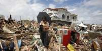 Mulher recupara ursinho de pelúcia em meio aos escombros do que restou do super tufão Haiyan em Tanauan, nas Filipinas. O saldo de mortos de um dos mais poderosos tufões do mundo aumentou nesta sexta-feira, mas a distribuição de ajuda está sendo tão irregular que corpos ainda não foram recolhidos e milhares de pessoas tentam desesperadamente sair das regiões afetadas na parte central das Filipinas. 14/11/2013.  Foto: Erik De Castro / Reuters