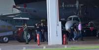 <p>Avião da PF com condenados do mensalão chega ao aeroporto de Brasília. Na foto, José Genoino (de camisa rosa) é conduzido por policiais federais</p>  Foto: Pedro França / Futura Press