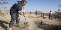 Trabalhadores escavam local em que os corpos da família foram encontrados, próximo a Victorville, em 15 de novembro  Foto: AP