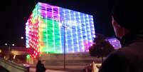 Jogador mexe em um cubo m&aacute;gico todo branco e movimenta as cores projetadas no pr&eacute;dio  Foto: Divulga&ccedil;&atilde;o