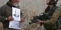 Palestino olha para policial israelense durante ato em homenagem a Mandela, perto de Ramallah  Foto: AP