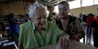 Mulher deposita voto em urna de seção eleitoral em Santiago  Foto: Reuters