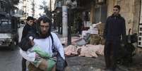 Homem carrega crian&ccedil;a retirada dos escombros ap&oacute;s bombardeios em Aleppo no dia 29 de dezembro de 2013  Foto: Reuters