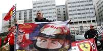 <p>F&atilde; franc&ecirc;s da Ferrari segura bandeira com a imagem de Schumacher em frente ao hospital</p>  Foto: Charles Platiau / Reuters