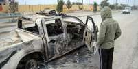  Homem olha carro após bombardeio que deixou mortos e feridos em Bagdá  Foto: AP