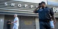 Segurança vigia shopping fechado no bairro do Leblon, no Rio de Janeiro. Dois centros de compras fecharam as portas devido a um "rolezinho" que ocorreria em um deles  Foto: Mauro Pimentel / Terra