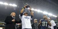 <p>Quarterback Russell Wilson ergue o trof&eacute;u da Confer&ecirc;ncia Nacional (NFC) ap&oacute;s vit&oacute;ria sobre os 49ers</p>  Foto: Reuters