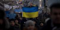 Homem exibe a bandeira ucraniana na Praça Independência, em Kiev, epicentro da mobilização opositora  Foto: AP