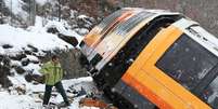 Trem  se chocou contra uma rocha que caiu na via e um dos vagões do trem virou  Foto: AFP