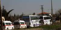 Famílias sírias deixam, em ônibus, a cidade de Homs, que virou um campo de batalha  Foto: AP