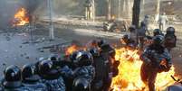Policiais mantêm posição enquanto são atingidos por fogo causado por coqueteis Molotov atirados pelos manifestantes, em Kiev  Foto: Reuters