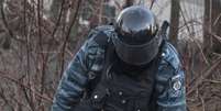 Policial observa manifestante ferido durante confrontos no centro de Kiev  Foto: Reuters