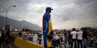 Manifestante vestindo bandeira venezuelana durante protesto da oposição que bloqueou ruas próximas ao aeroporto La Cartola, em Caracas, em 18 de fevereiro  Foto: AP