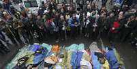 Pessoas rezam próximas aos corpos de manifestantes contrários ao governo mortos durante os confrontos em Kiev  Foto: Reuters