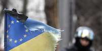 <p>Em gesto simbólico, uma fita preta foi colocada em uma bandeira que combina as bandeiras da Ucrânia e da União Europeia. A simbologia marca um dia de luto nas ruas de Kiev</p>  Foto: Reuters