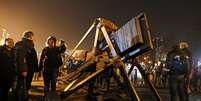 Manifestantes antigoverno discutem próximos a uma catapulta improvisada na Praça da Independência, em Kiev  Foto: Reuters