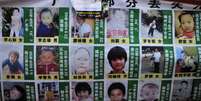 <p>Mulher segura vela e&nbsp;um cartaz que mostra fotos de crian&ccedil;as desaparecidas, na prov&iacute;ncia central chinesa de Hubei, em 24 de janeiro 2010</p>  Foto: AP