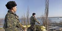 Soldados de fronteira vigiam a entrada da base naval de Novoozernity. Houve denúncias de que a Rússia teria bloqueado canal que separa da Crimeia   Foto: EFE