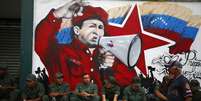 Soldados venezuelanos sentam em frente a um mural com a imagem de Hugo Chávez, em 27 de fevereiro  Foto: Reuters