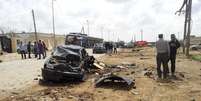 Homens observam carro destruído por explosão de bombas que mataram pelo menos 5 e feriram outros 10 na cidade de Benghazi, ao leste da Líbia  Foto: Reuters