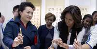 Peng Liyuan tenta ensinar Michelle Obama a reproduzir um caractere chinês  Foto: AP