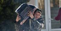 Soldado ucraniano carrega uma televisão enquanto deixa a base militar de Belbek, perto de Sebastopol, Crimeia, nesta sexta-feira  Foto: AP
