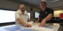 <p>Mike Barton (esq.), que comanda a equipe de resgate australiana, mostra a encarregado das operações um mapa da região em que as buscas são realizadas no Oceano Índico: 26 países estão envolvidos</p>  Foto: AP