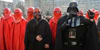 <p>Homem, vestido de Darth Vader, que anunciou que está concorrendo à presidência da Ucrânia como candidato oficial do Partido Internet ucraniano (UIP) e outro vestindo a roupa do Darth Maul, cercados por homens vestidos como o imperador Royal Guards participam de uma ação de protesto em frente ao edifício da Comissão Eleitoral Central, em Kiev, nesta quinta-feira, 3 de abril</p>  Foto: AFP