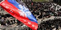 <p>A bandeira da chamada "República Federativa Donetsk" foi colocada em cima de uma barricada, e uma multidão de militantes pró-Rússia se reuniu em frente ao prédio da administração regional de Donetsk, nesta terça-feira, 8 de abril</p>  Foto: AFP