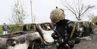 Soldado passa próximo a carro incendiado durante tiroteio na madrugada deste domingo na cidade ao leste da Ucrânia  Foto: Reuters