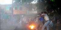 <p>Espectadores indianos tentam apagar o fogo do corpo de um homem chamado pela polícia como Durgesh Kumar Singhb, durante um debate eleitoral televisionado, em um parque local da cidade de Sultanpur, na Índia</p>  Foto: AFP