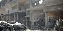 Pessoas se aproximam de local onde dois carros bombas explodiram nesta terça-feira em Homs  Foto: Reuters