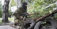 <p>Um homem armado pro-russo corre atr&aacute;s de barricadas segurando uma arma na cidade de&nbsp;Slovyansk, leste da Ucr&acirc;nia, nesta sexta-feira, 2 de maio</p>  Foto: AP