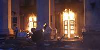 <p>Um manifestante joga um coquetel molotov em prédio em chamas, na cidade de Odessa, na Ucrânia, em 2 de maio</p>  Foto: Reuters