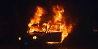 Grupos de manifestantes encapuzados atearam fogo na segunda-feira à noite em um veículo militar na Venezuela  Foto: AFP