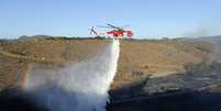 <p>Helicóptero despeja água em uma das áreas atingidas por incêndio, ao norte de San Diego, nesta terça-feira, 13 de maio</p>  Foto: Reuters