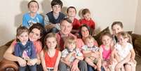 Nem todos os membros da família estão na imagem; Sue e o marido, ao centro, têm 16 filhos e esperam outro  Foto: Daily Mail / Reprodução