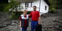 Casal fica em frente a sua casa na cidade de Topcic Polje, Bósnia; país calcula prejuízos de milhões de reais  Foto: Reuters