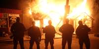 <p>Combatentes pró-Rússia posam para foto em frente a um café em chamas durante os combates com as tropas do governo ucraniano em um posto de controle perto da estrada principal que liga Kharkiv, fora de Slovyansk, em 22 de maio</p>  Foto: AP